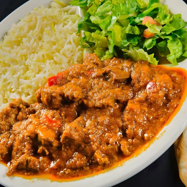 Mimi's Kabob's Afghan curry with rice and a side salad on a white plate.