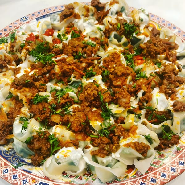 Mimi's Kabob's Afghan Mantu dumplings, topped with ground meat sauce, yogurt, and fresh herbs.