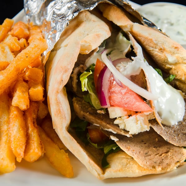 A Mimi's Kabob gyro with meat, lettuce, tomato, onion, feta, and sauce, served with fries.