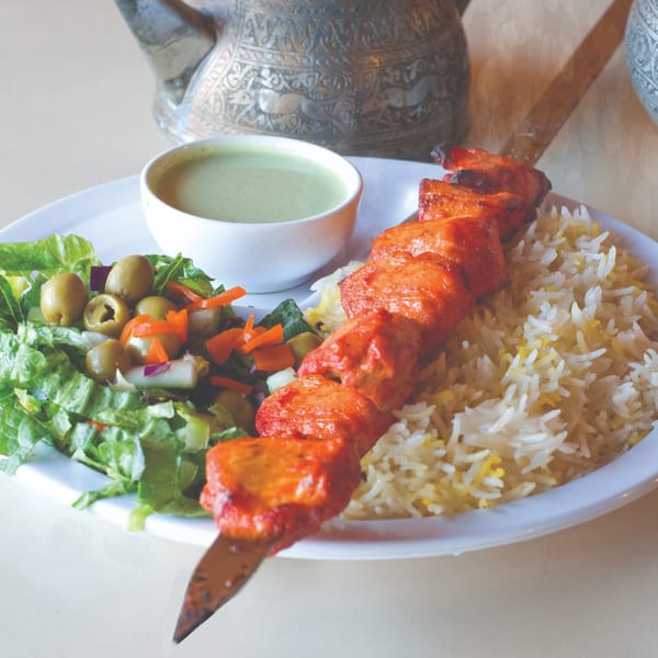 Mimi's Kabob chicken skewer with rice, green salad, and a side of green sauce.