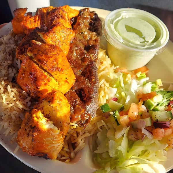 Mimi's Kabob platter with chicken and beef kabobs, rice, salad, and a side of green sauce.