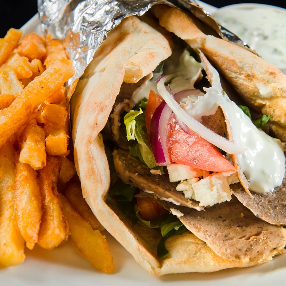 Mimi's Kabob gyro with meat, lettuce, tomato, onion, feta, and white sauce, served with fries.