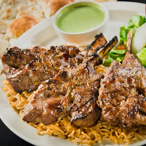 Mimi's Kabob lamb chops with rice, green sauce, salad, and naan bread.