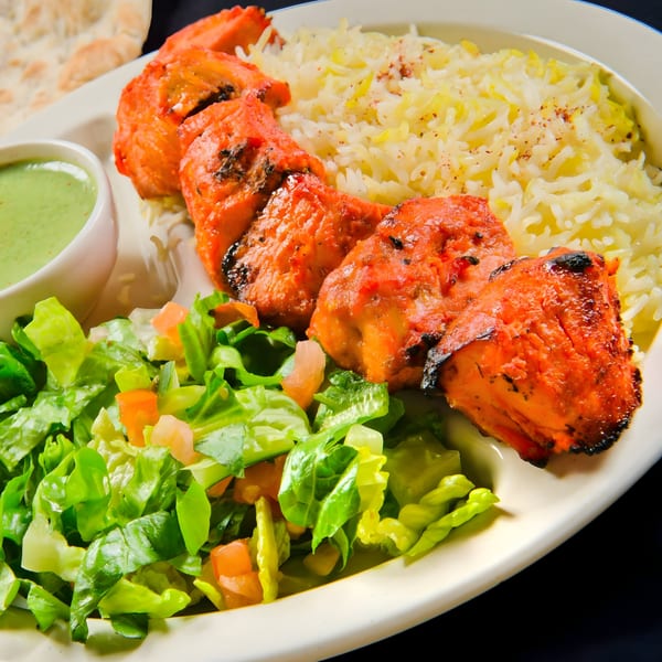 Mimi's Kabob chicken tikka with rice, green salad, and a side of green sauce.