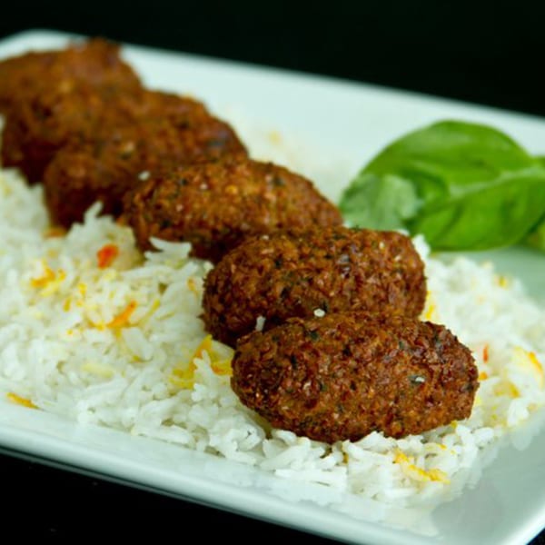 Mimi's Kabob's Afghan falafel, served with white rice and a green garnish on a white plate.