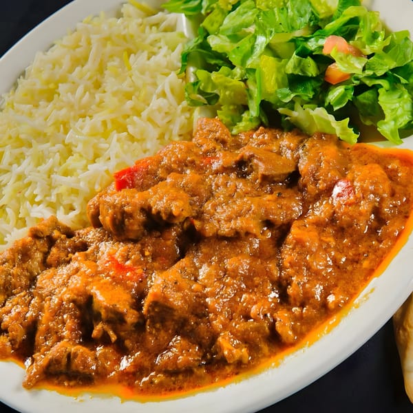 Mimi's Kabob's Afghan dish with saucy meat, white rice, and a side salad.