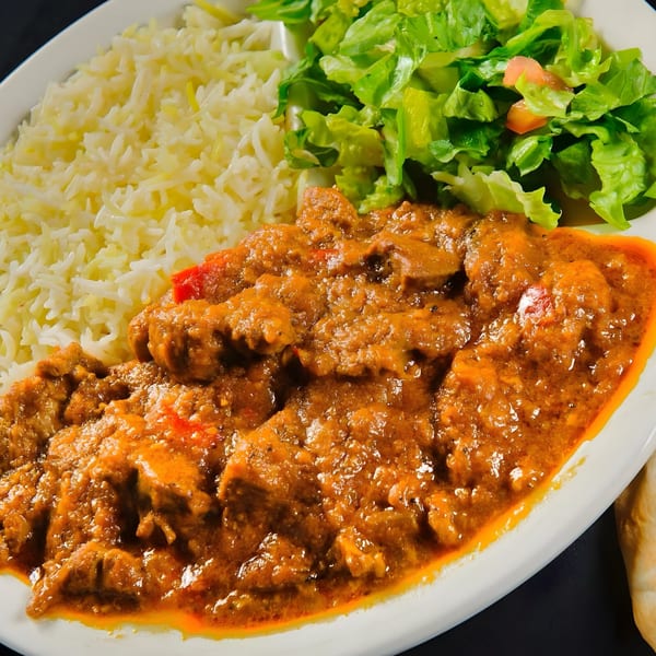 Mimi's Kabob's Afghan curry with rice and a side salad on a white plate.