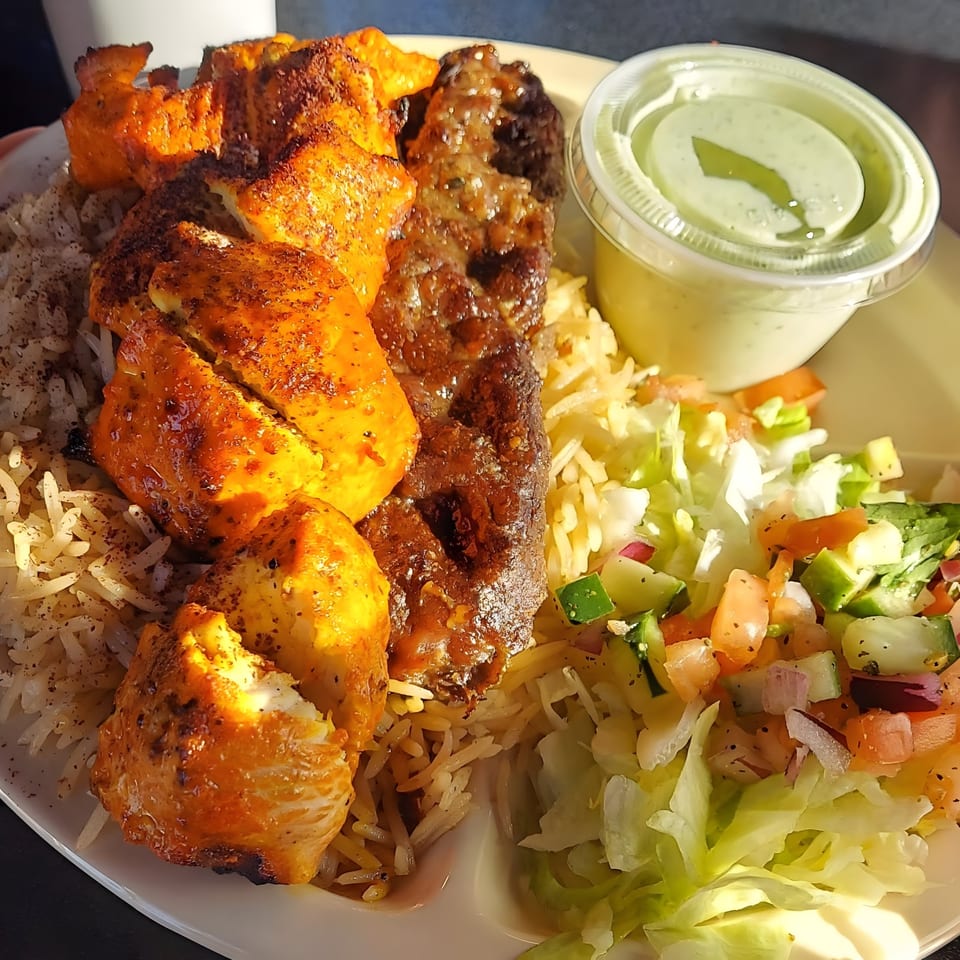 Mimi's Kabob platter with chicken and beef kabobs, rice, salad, and a side of green sauce.